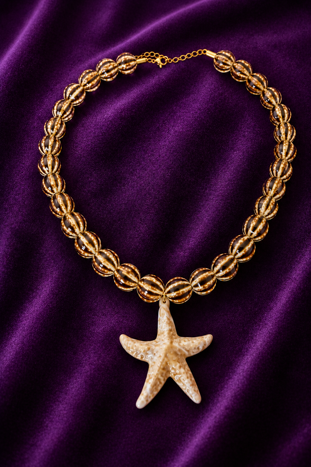 Collar Estrella de Mar de cerámica con cuentas rayadas beige y marrón y colgante de estrella marfil sobre fondo morado | Zeyala